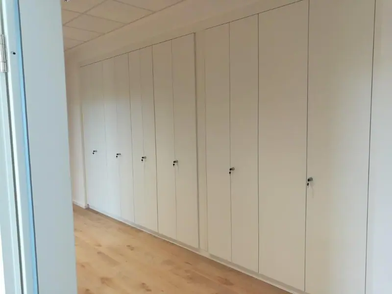 Raumhohe weiße Einbauschränke über eine ganze Wand