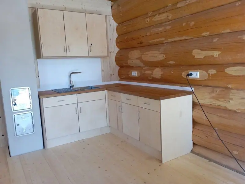 Küchenzeile in hellem Holz an einer Blockbohlenwand