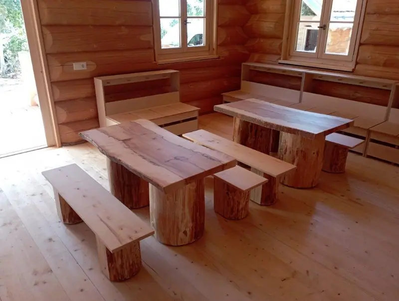 Langer Holztisch mit Bänken auf Füßen aus Rundholz in einem hellen Raum